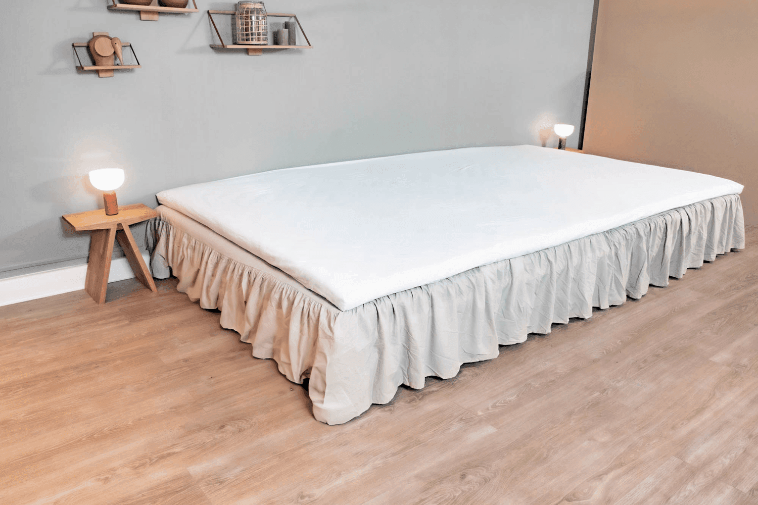 Beige FAMBED®-helmalakana sängyn sivulla
